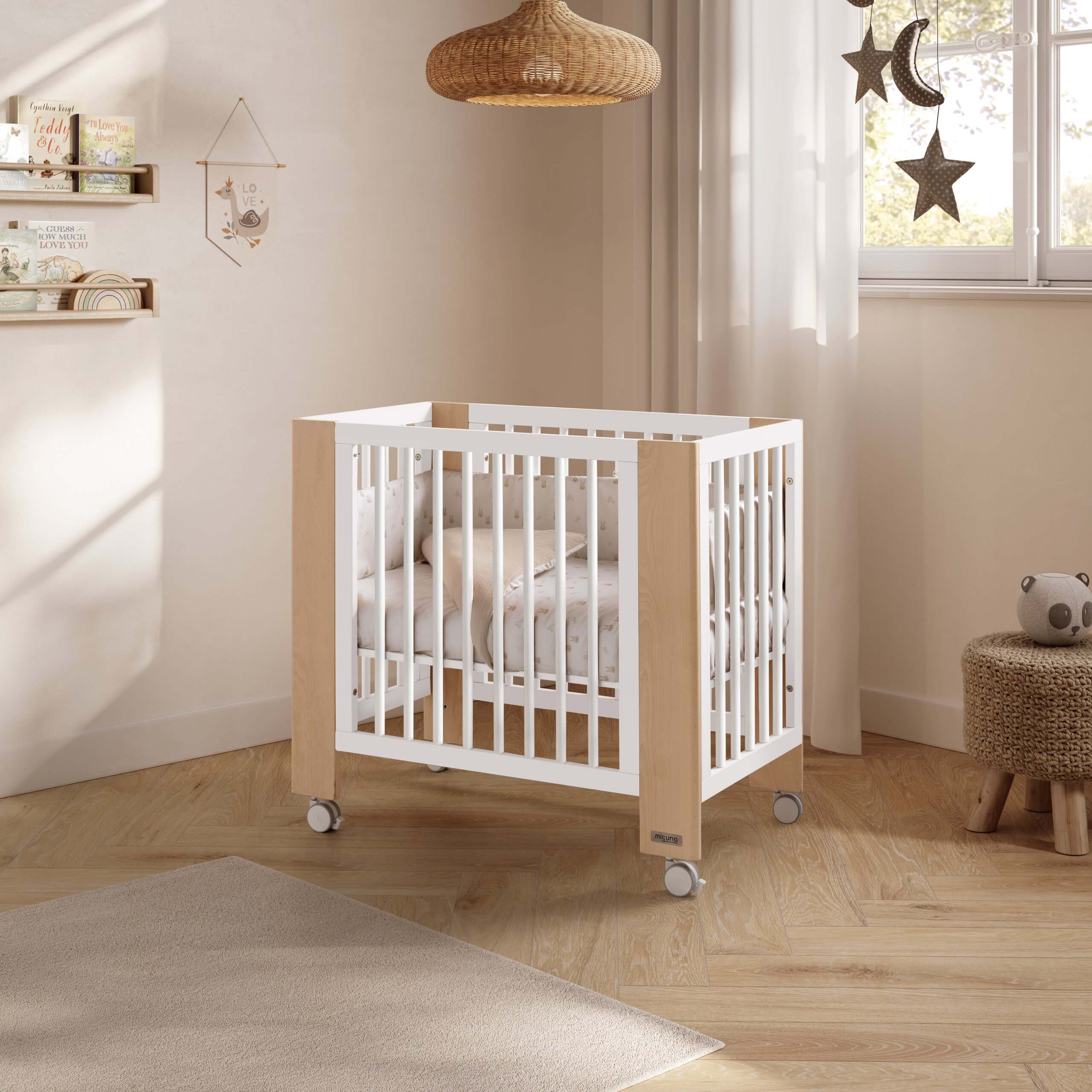 Mini-berço Micuna Converbaby de co-sleeping em madeira clara e branco, montado num quarto de bebé com decoração neutra.