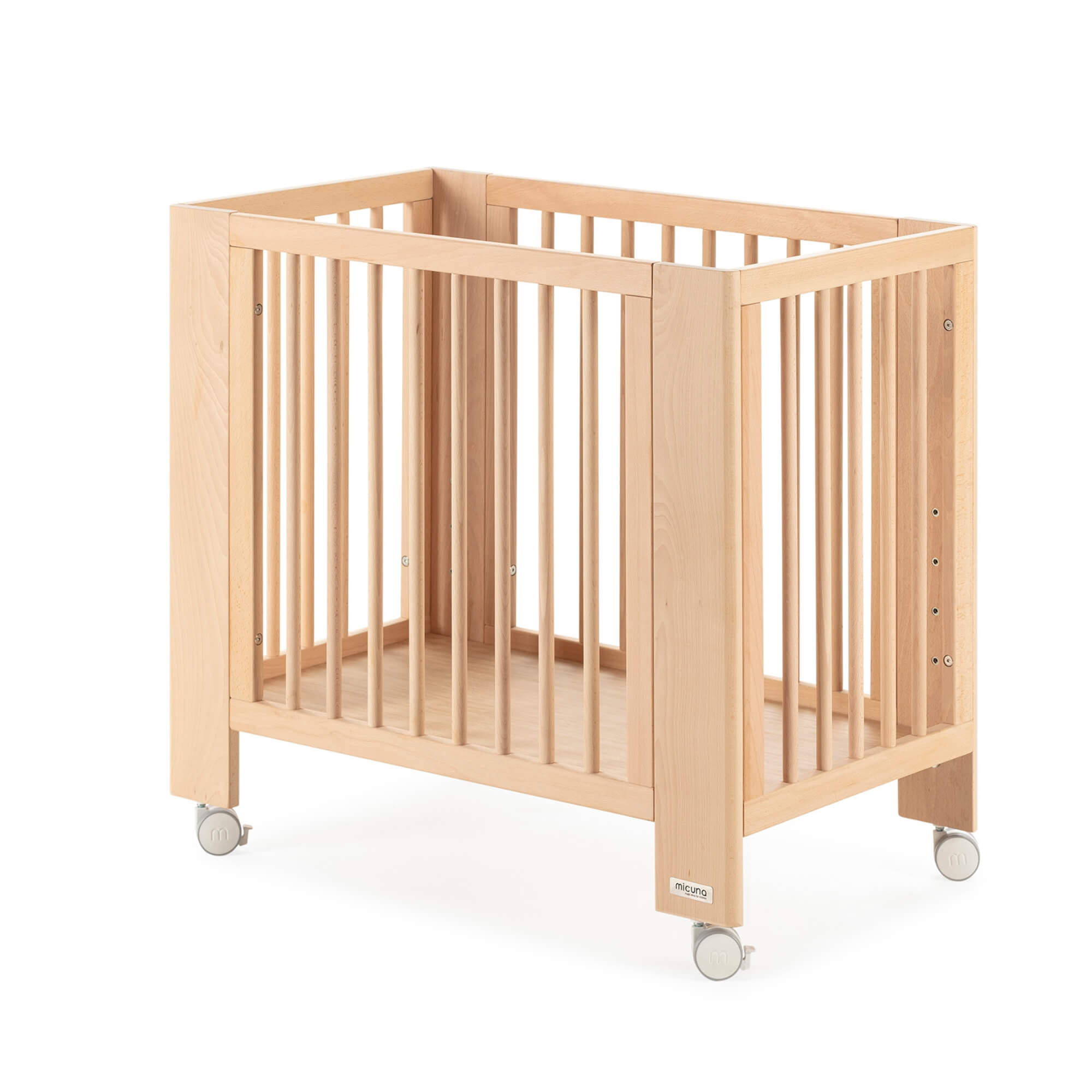 Mini-berço Micuna Converbaby 90x50 em madeira natural, visto de lado, com rodas e estrutura simples, sobre fundo branco.