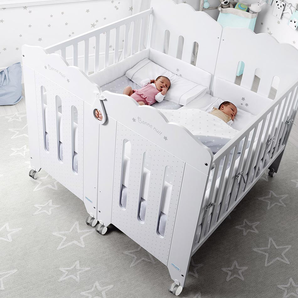 Vista aérea de duas camas de bebé Micuna unidas pelo Kit Duo Gêmeos, com dois bebés gémeos a dormir lado a lado.