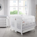 Quarto de bebé com duas camas Micuna brancas de 120x60 unidas pelo Kit Duo Gêmeos, com um bebé a dormir.