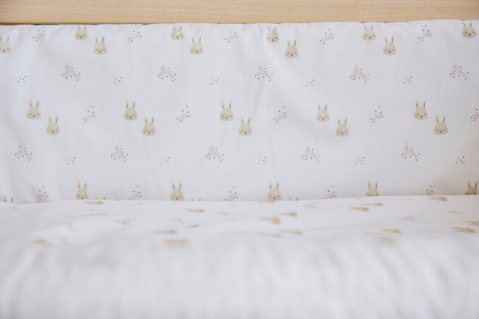 Detalhe do tecido branco do Kit Micuna nórdico e protector para minicuna 80x50, com padrão de pequenos coelhos e pontos.