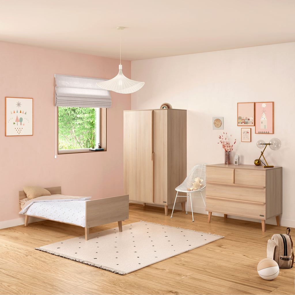 Armário Micuna Martha em carvalho no quarto de criança, ao lado de berço e cómoda da coleção, ambiente rosa suave.
