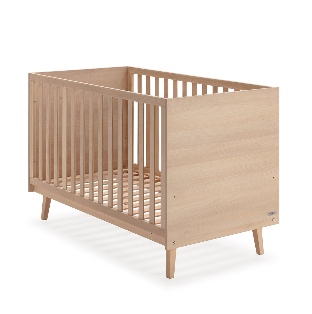 Berço Micuna Martha 120x60 em madeira de faia clara, vista frontal ligeiramente angulada, com o logótipo Micuna na lateral.