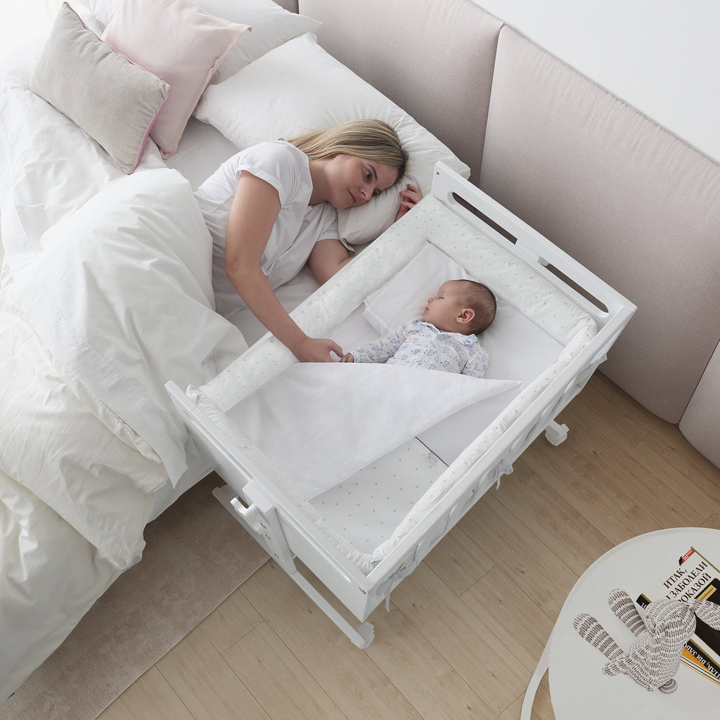 Mãe a interagir com bebé a dormir tranquilamente no mini-berço Micuna You and Me Plus em modo co-sleeping.