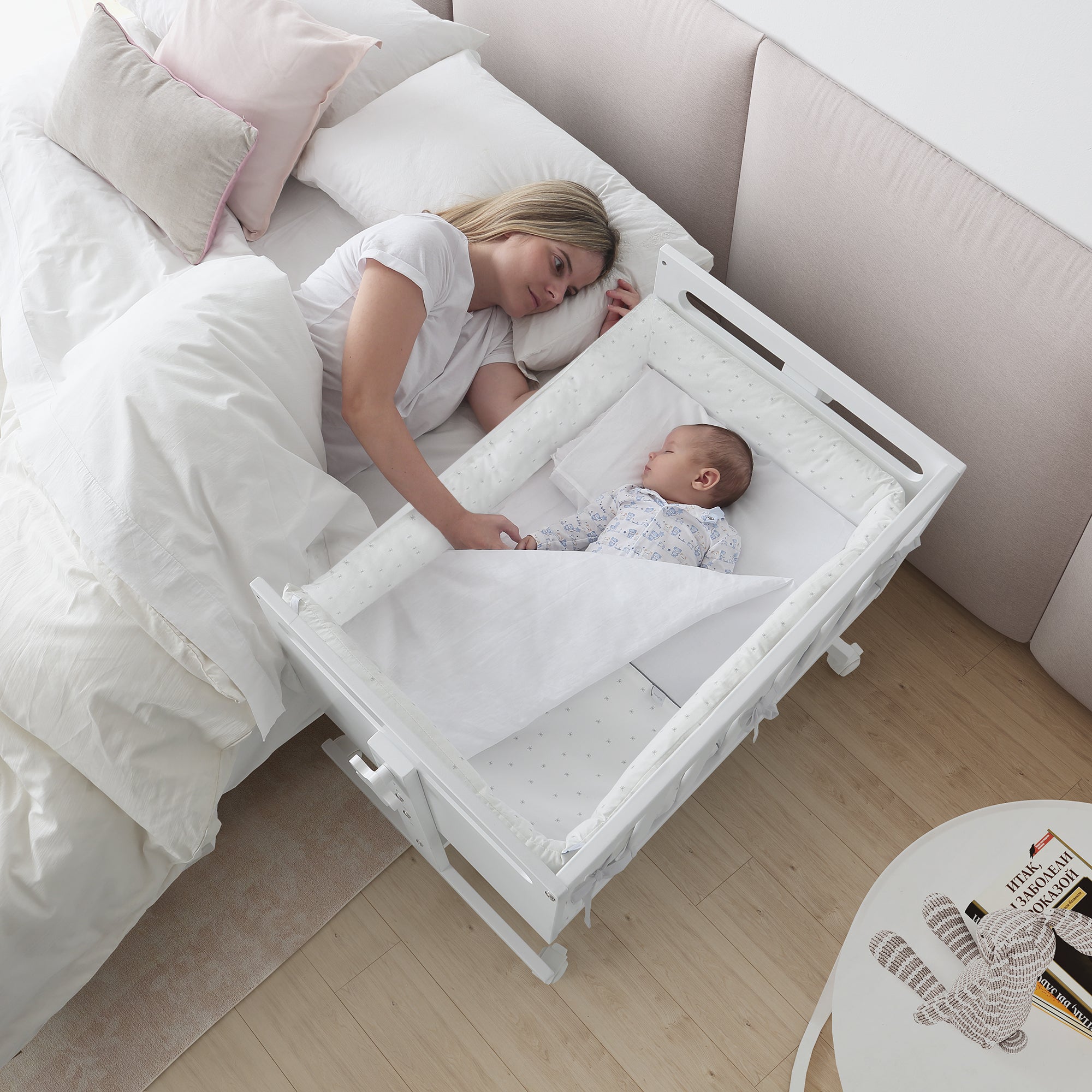 Mãe a interagir com bebé a dormir tranquilamente no mini-berço Micuna You and Me Plus em modo co-sleeping.