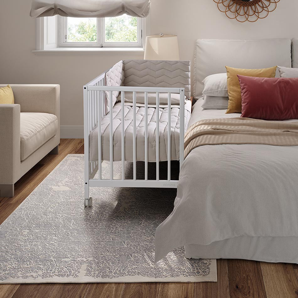 Micuna Mountain Berço 120x60 branco num quarto de bebé moderno, com trocador e decoração.