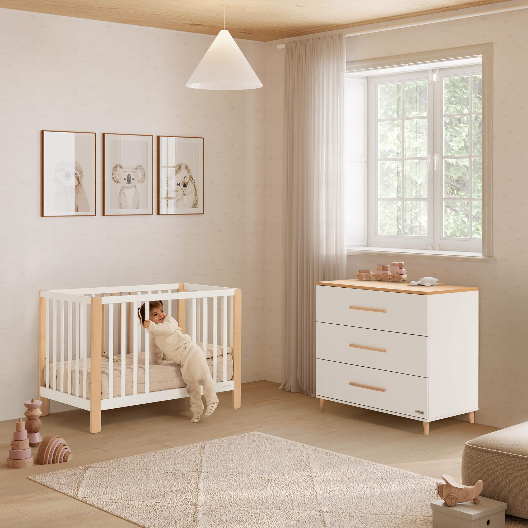 Berço Micuna Nayra de 120 x 60 em branco e madeira, com criança a sair, ao lado de uma cómoda a condizer num quarto infantil.