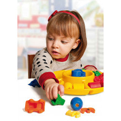 Criança pequena a usar a bandeja de separação Miniland amarela para classificar peças de construção coloridas, desenvolvendo a motricidade fina.