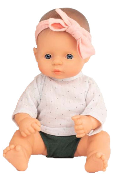 Boneca bebé caucasiana Miniland de 32cm, sentada, com cabelo louro, olhos azuis e laço rosa na cabeça.