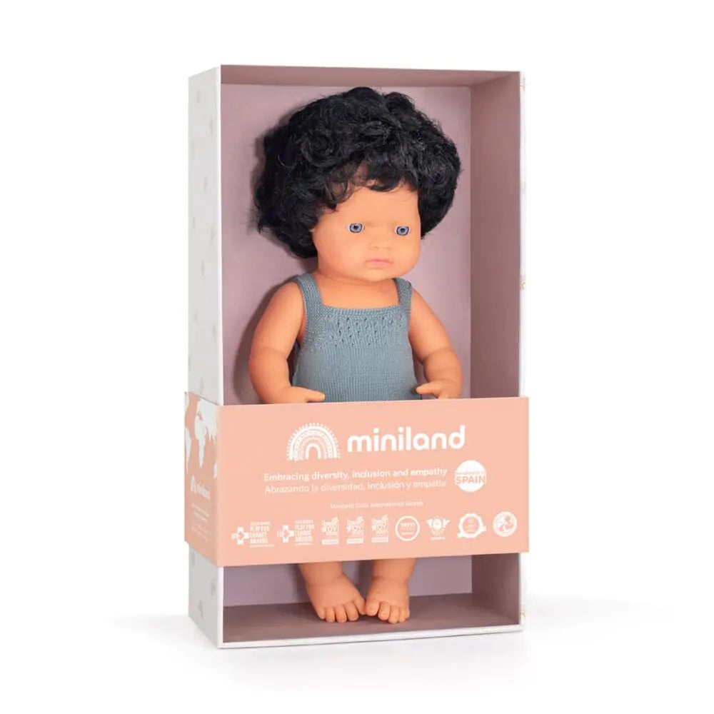 Boneco bebé Miniland caucasiano com cabelo preto dentro da sua caixa de apresentação, destacando a marca e o compromisso com a diversidade.