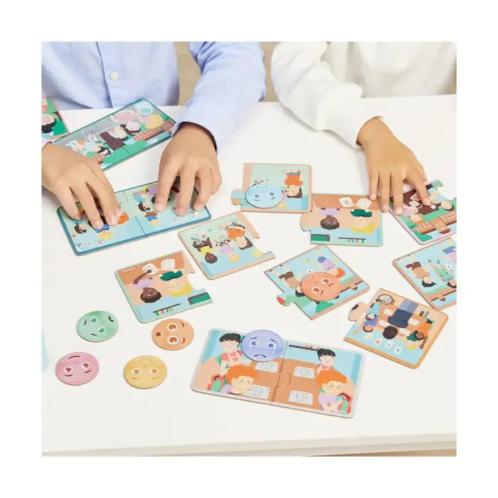 Duas crianças brincam com o Miniland Jogo de Emotiduos, encaixando peças de puzzle e associando rostos de emoções a cenários.