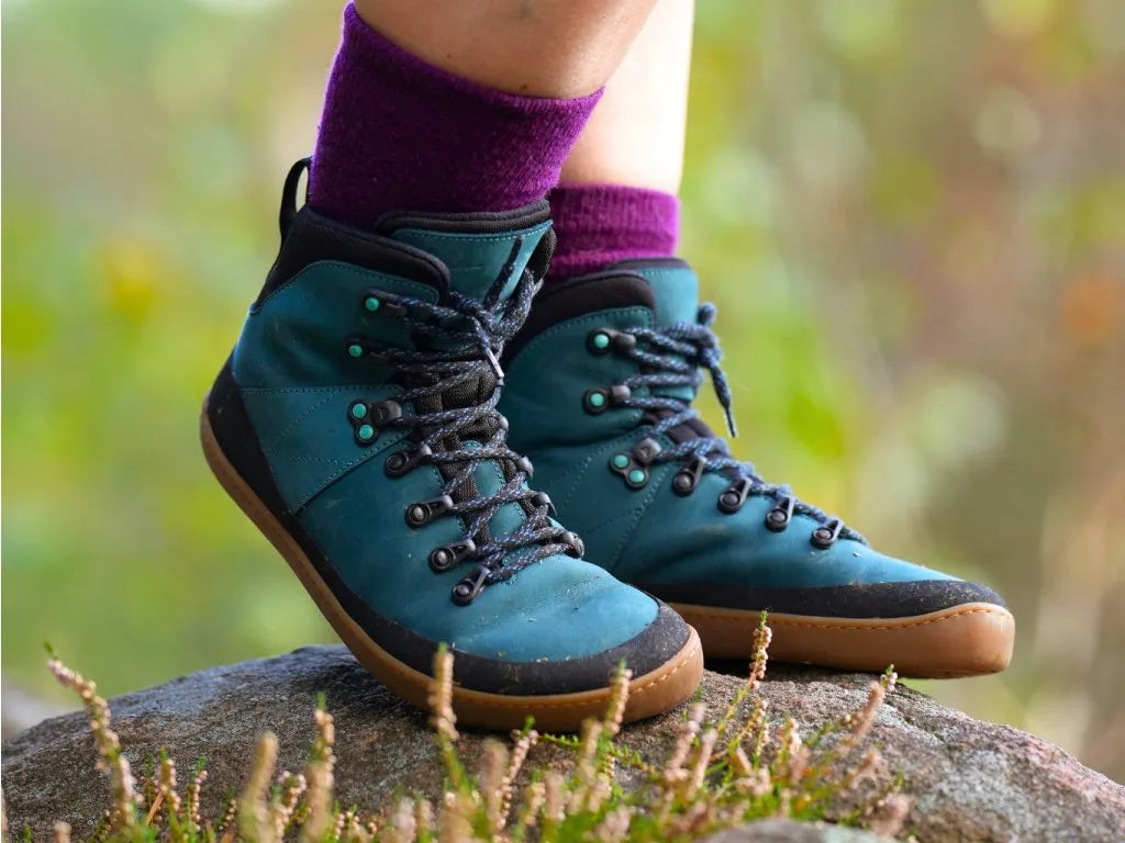 Detalhe das botas MITU barefoot femininas em azul petróleo nos pés de uma utilizadora, mostrando a flexibilidade e conforto.

