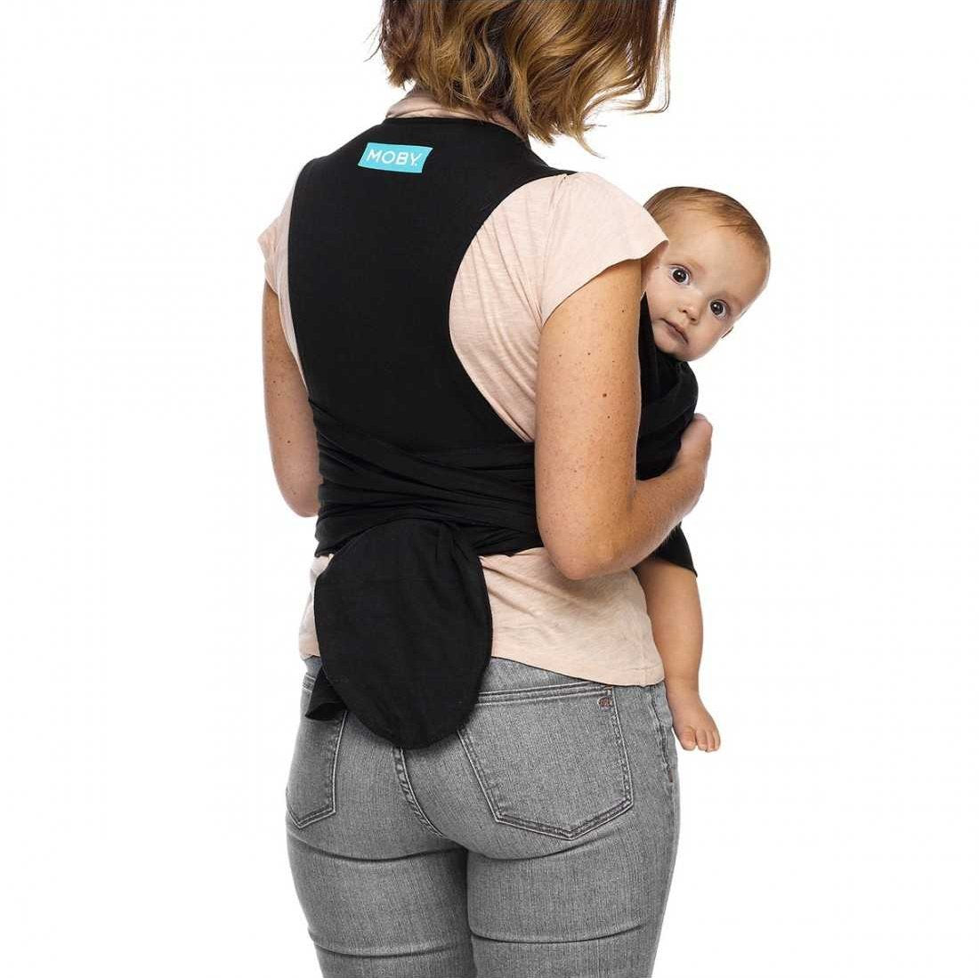 Vista traseira de uma mulher a usar a Mochila de Pano Elástico Moby FIT Black, com o bebé posicionado confortavelmente.