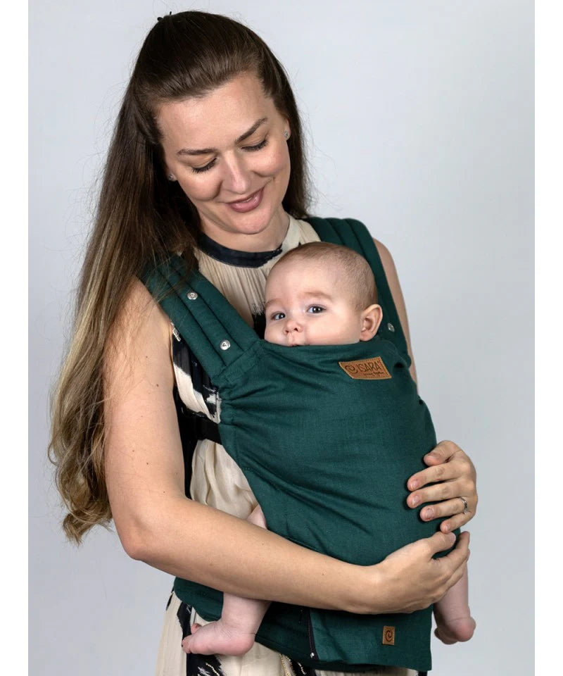 Uma mãe a olhar para o bebé na Mochila Isara Elite Ajustável Evergreen Linen, destacando o conforto e a proximidade.