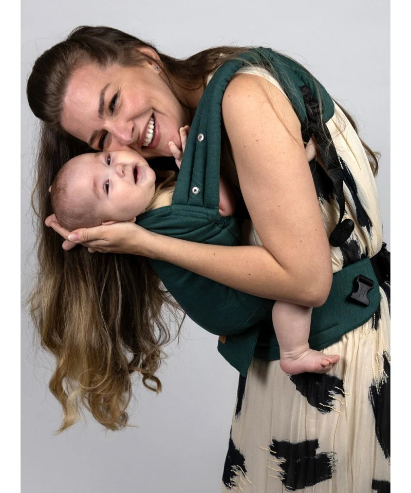 Uma mãe a interagir carinhosamente com o bebé que está na Mochila Isara Elite Ajustável Evergreen Linen, numa posição lateral.