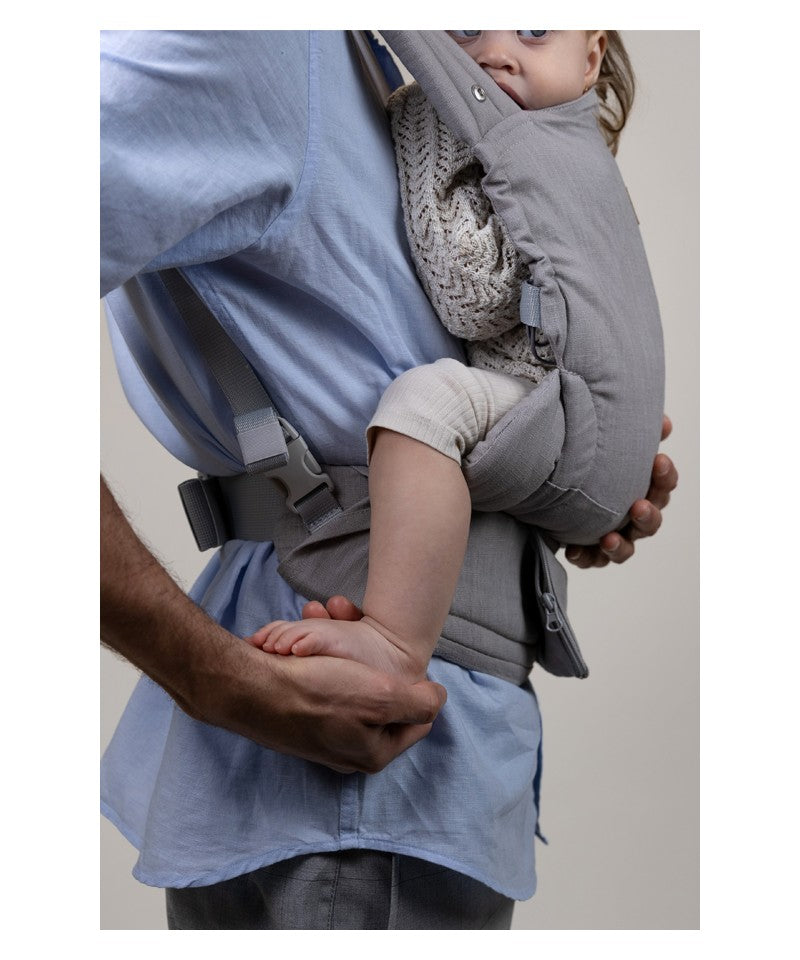 Detalhe da mochila Isara ELITE cinza sendo ajustada por um pai, mostrando o suporte ergonómico na perna e pé do bebé.