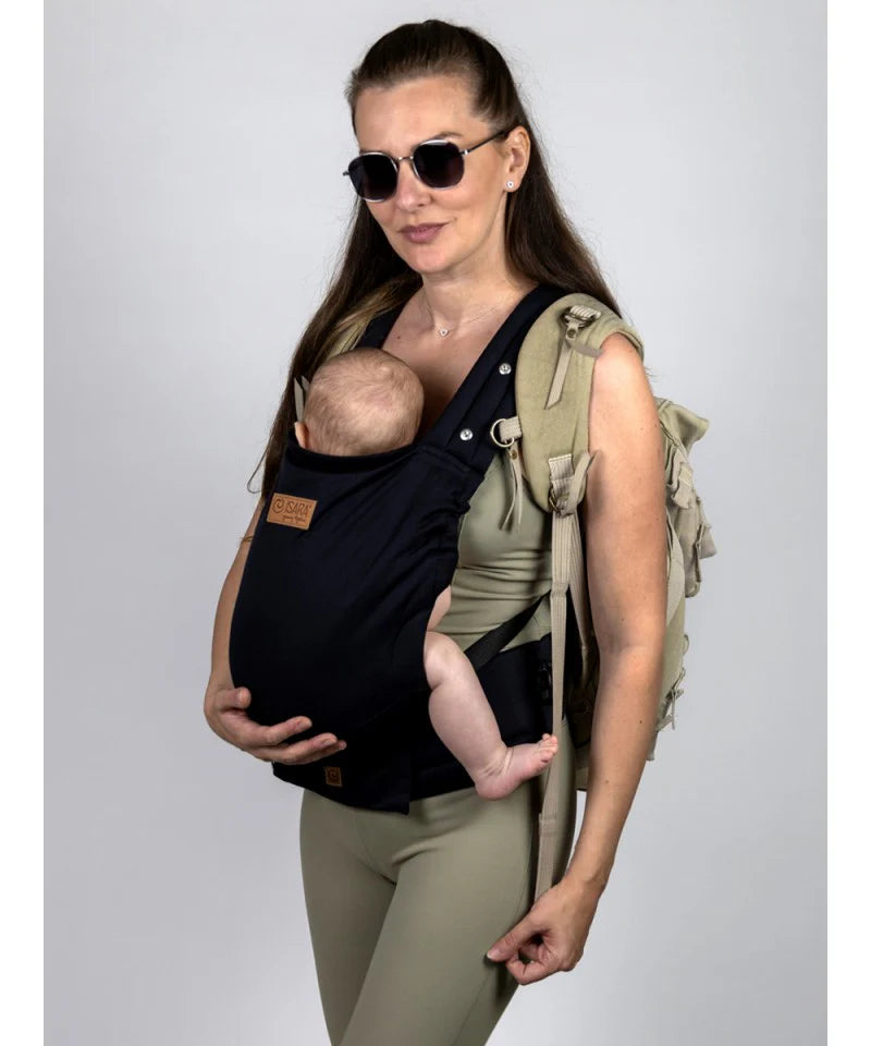 Uma mulher usando a mochila Isara Elite Noire, carregando um bebé recém-nascido na posição frontal.