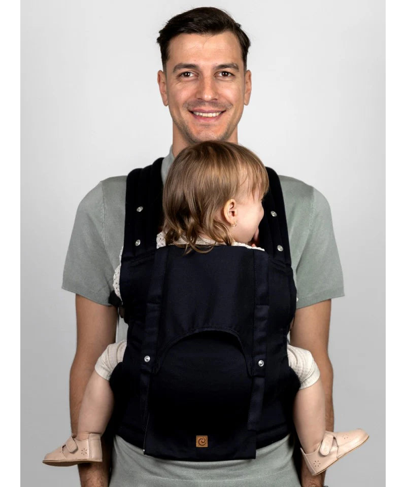 Um homem usando a mochila Isara Elite Noire, carregando uma criança mais velha na posição dorsal.