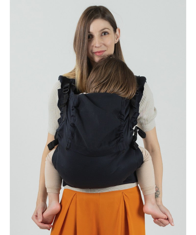 Mulher a usar a mochila Isara Toddler Preschooler Noire com uma criança a dormir às costas, vista frontal.