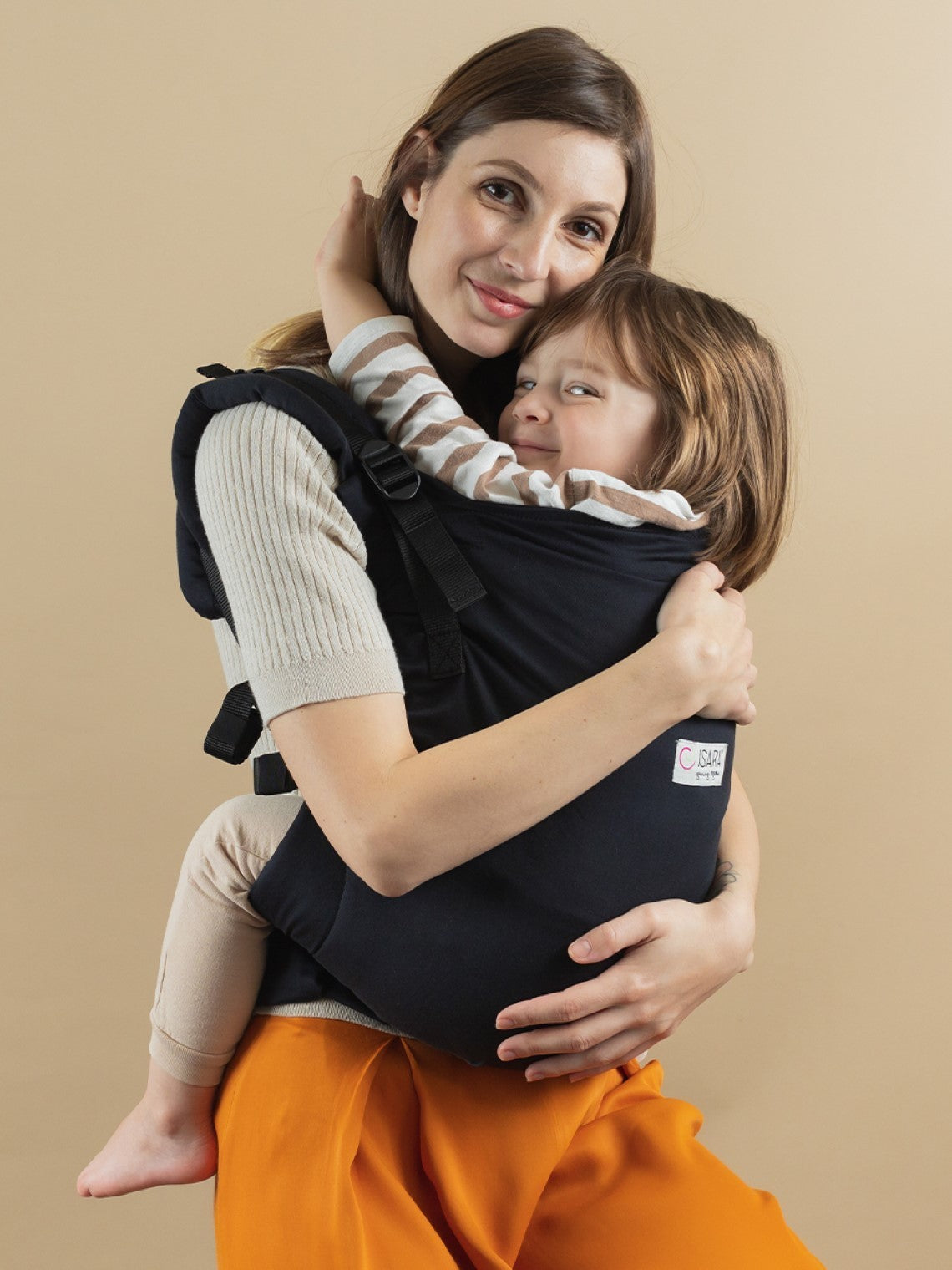 Mulher a usar a mochila Isara Toddler Preschooler Noire com uma criança na posição frontal, vista frontal, mais próxima.