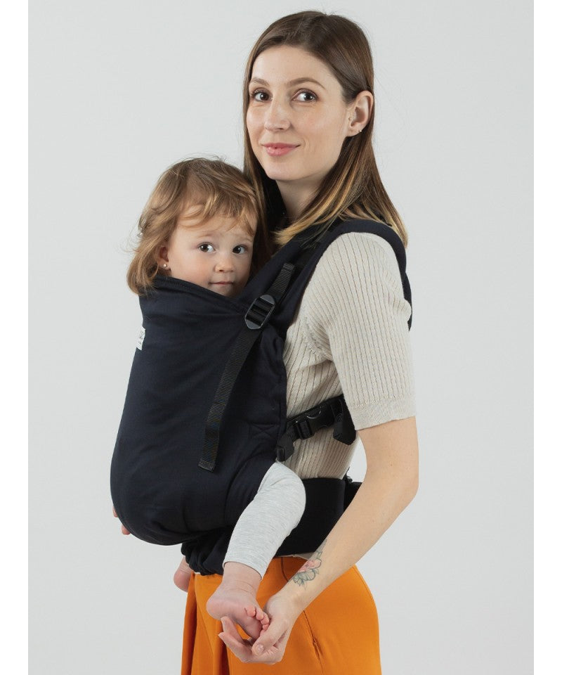 Mulher a usar a mochila Isara Toddler Preschooler Noire com uma criança na posição frontal, vista lateral.