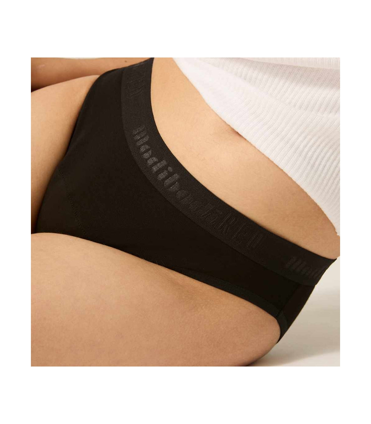 Detalhe da cueca menstrual Modibody preta, mostrando o logo e a tecnologia de absorção.