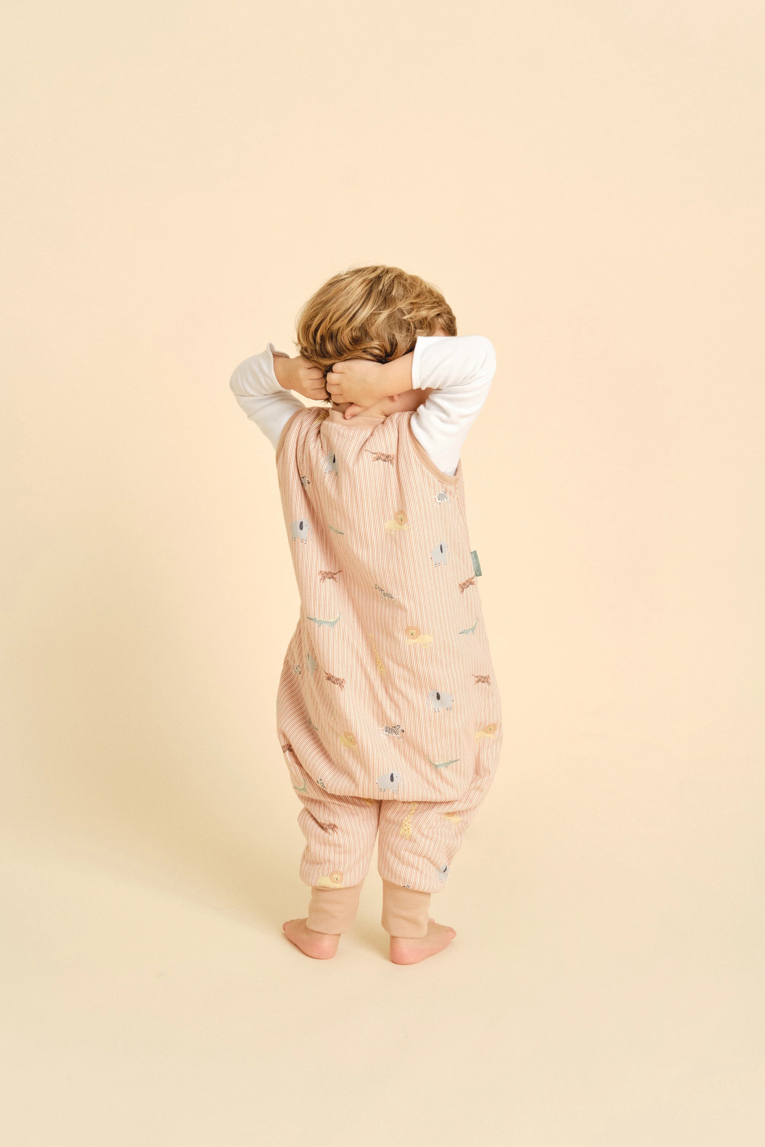 Criança de costas com saco de dormir MolisandCo TOG 1.0 Jungle, mãos na nuca, mostrando design.