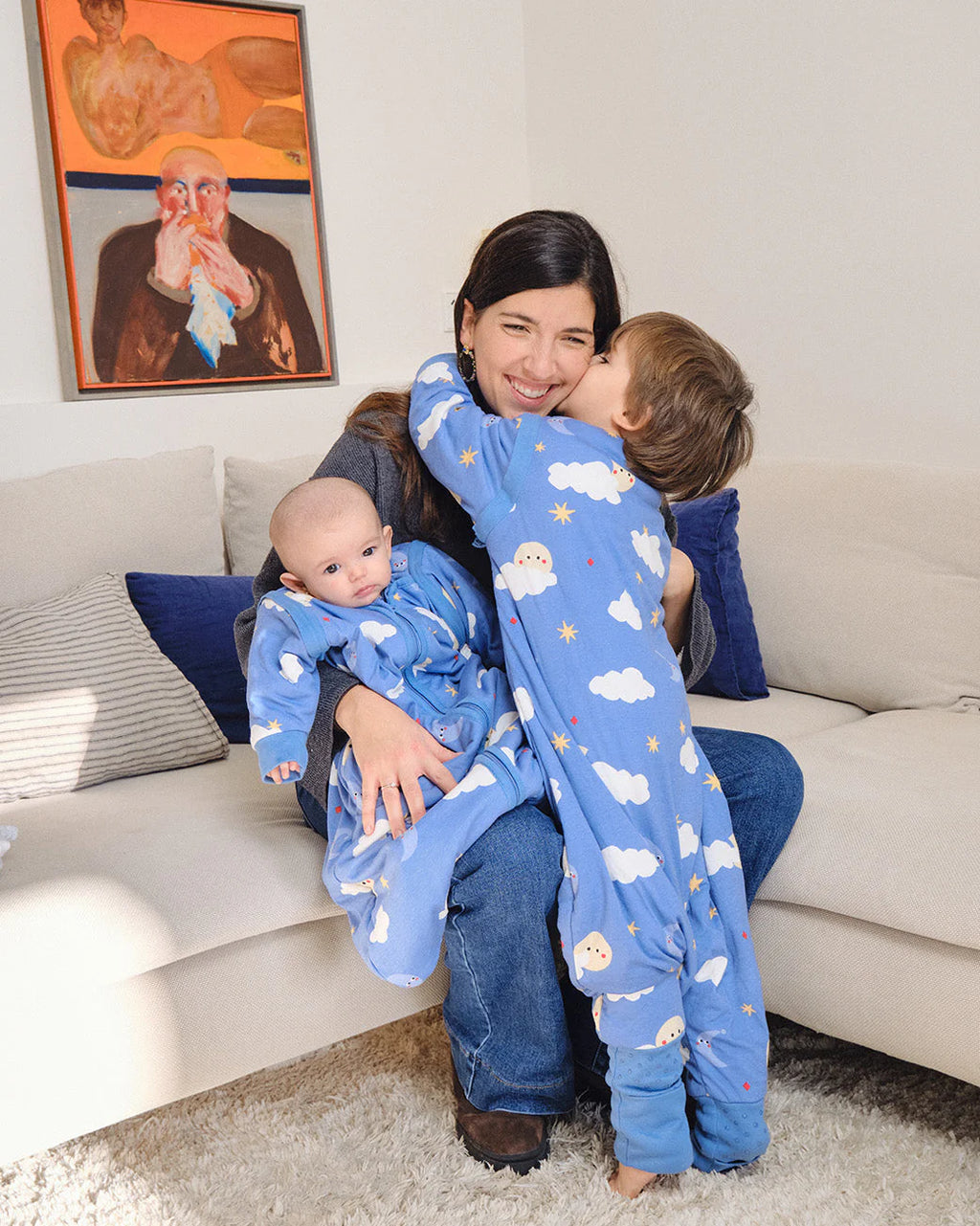 Mãe abraça os dois filhos, um bebé e uma criança mais velha, ambos com sacos de dormir MolisandCo, um deles com o padrão azul "Good Night".