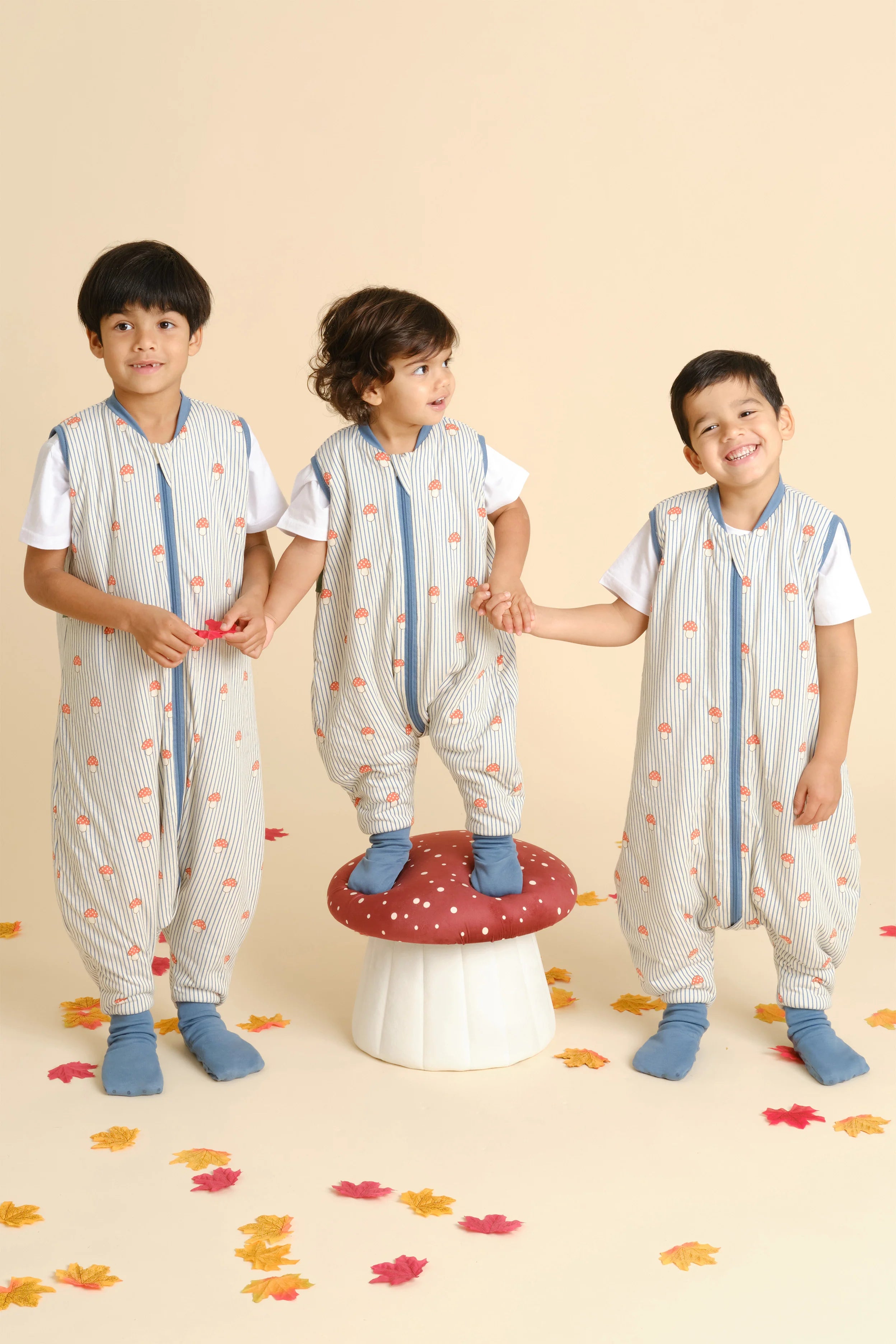 Três crianças de diferentes idades com sacos de dormir MolisandCo TOG 1.0 [Mushrooms], a brincar livremente.
