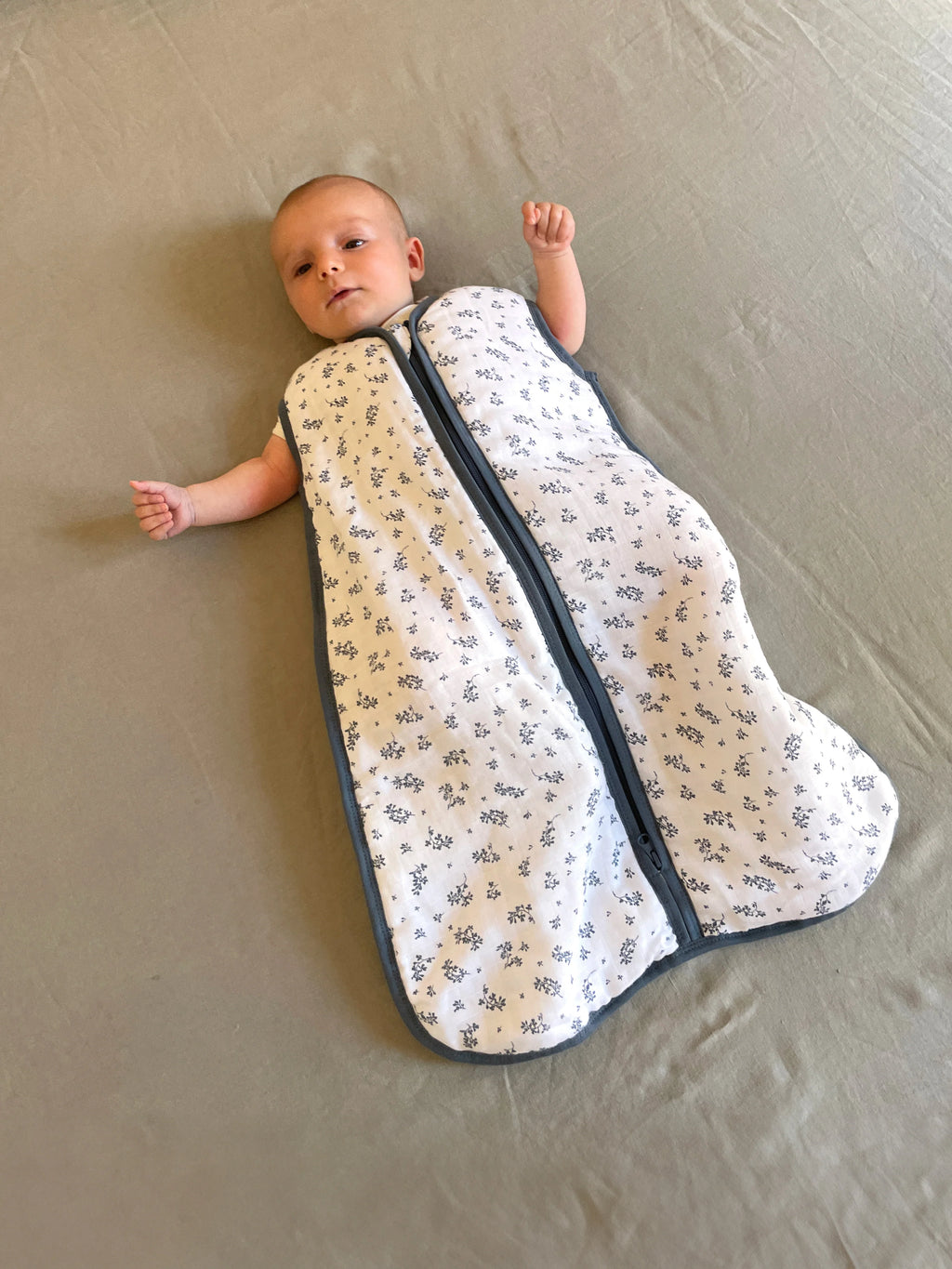 Bebé deitado confortavelmente no saco de dormir MolisandCo TOG 1.0, algodão musselina, padrão floral.