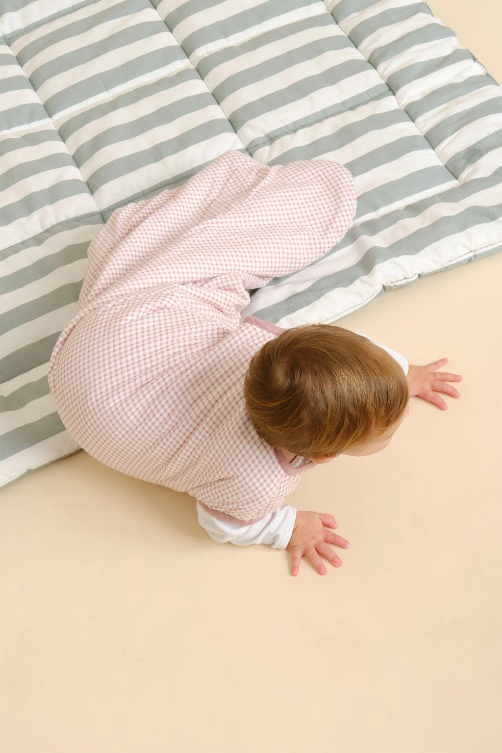 Bebé deitado de bruços no saco de dormir MolisandCo TOG 1.0 sem pés, padrão Vichy Pink, visto de cima.