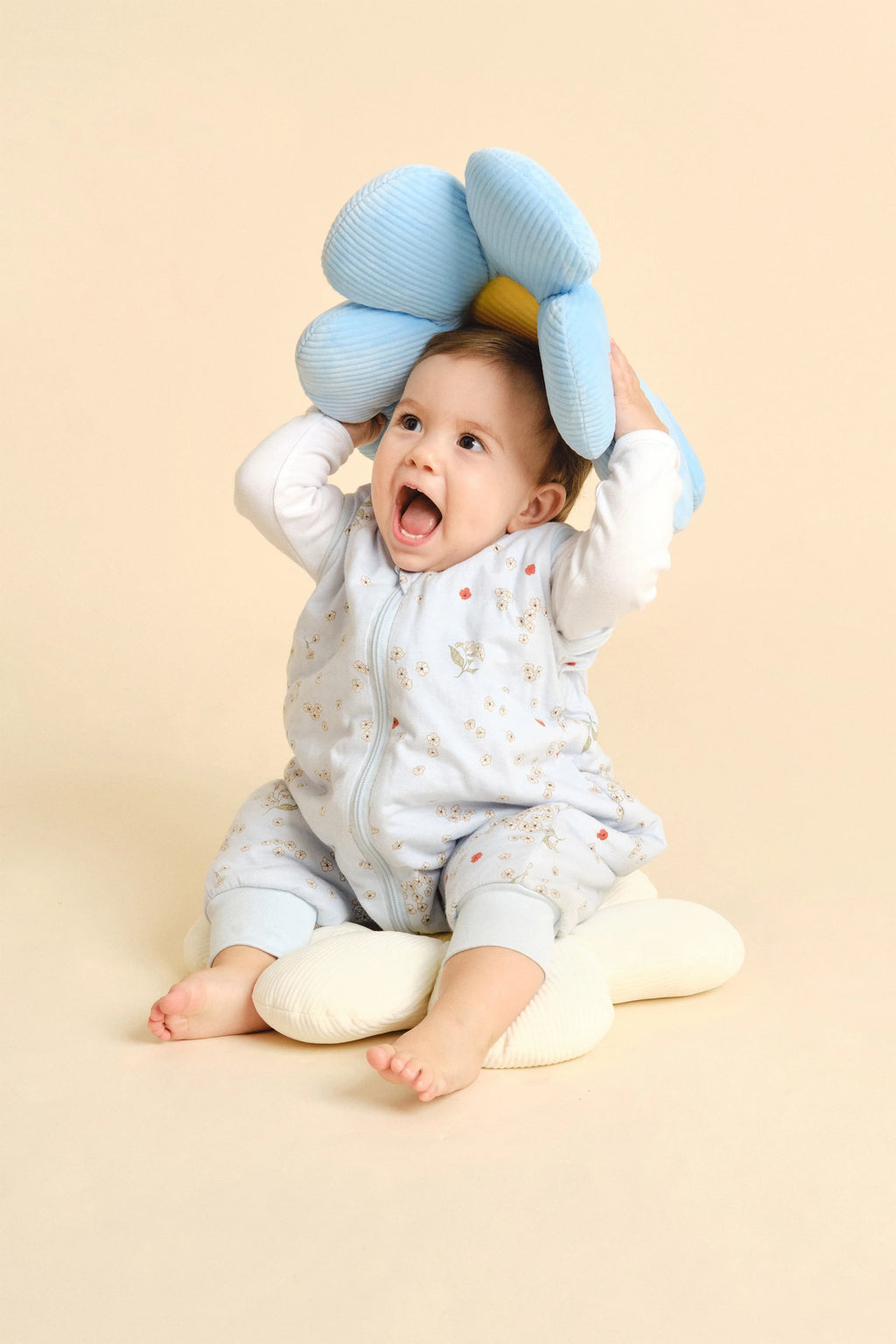 Bebé sentado, feliz, a brincar com almofada, usando saco de dormir MolisandCo TOG 1.0 Poppy.
