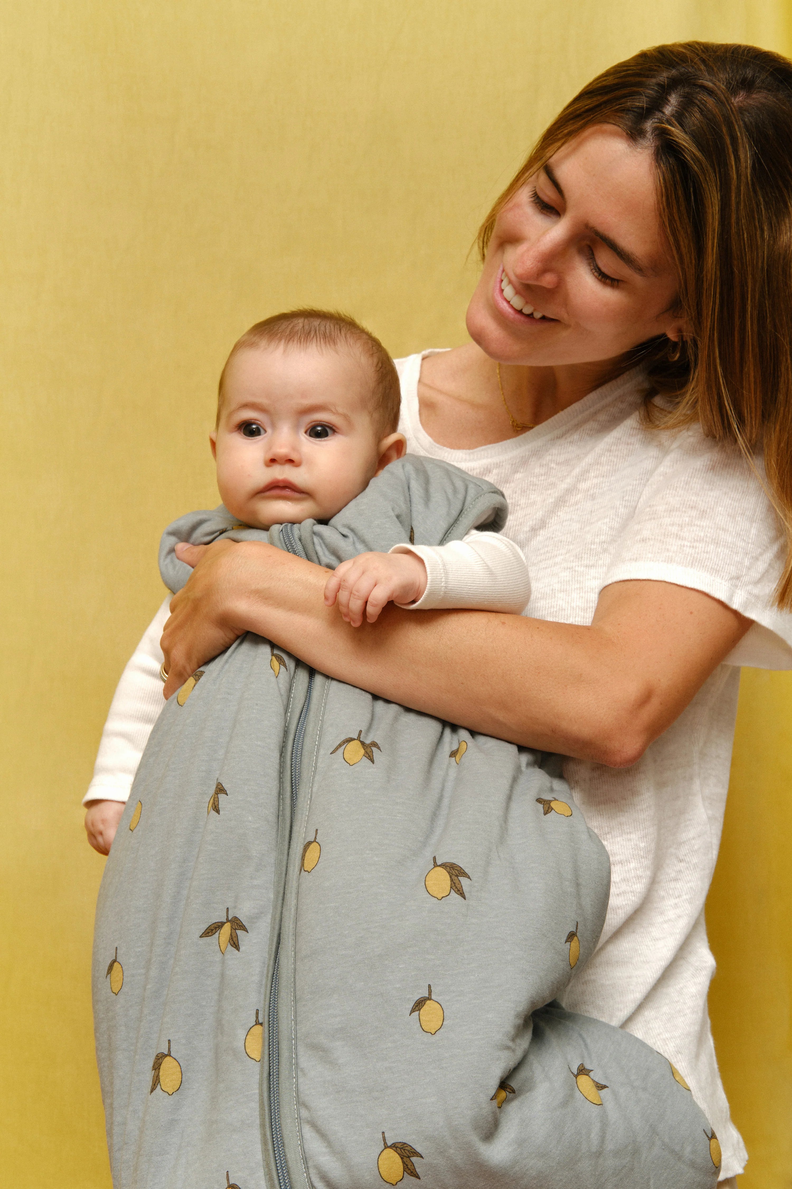Bebé aconchegado no saco de dormir MolisandCo Colima, azul com padrão de limões, tecido macio. Ideal para o inverno.