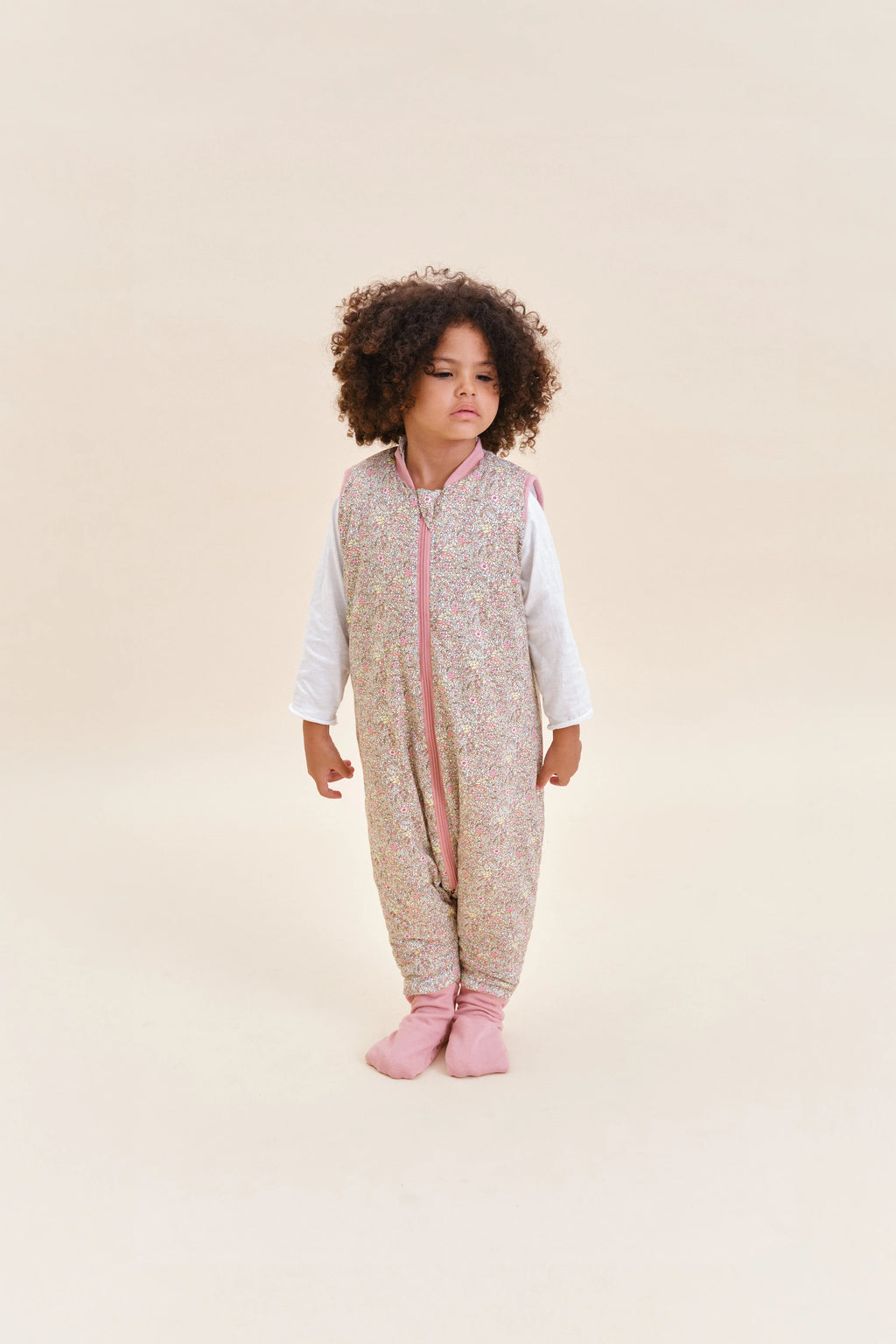 Criança com saco de dormir MolisandCo TOG 2.5 Pastel Floral e meias antiderrapantes, em pé.