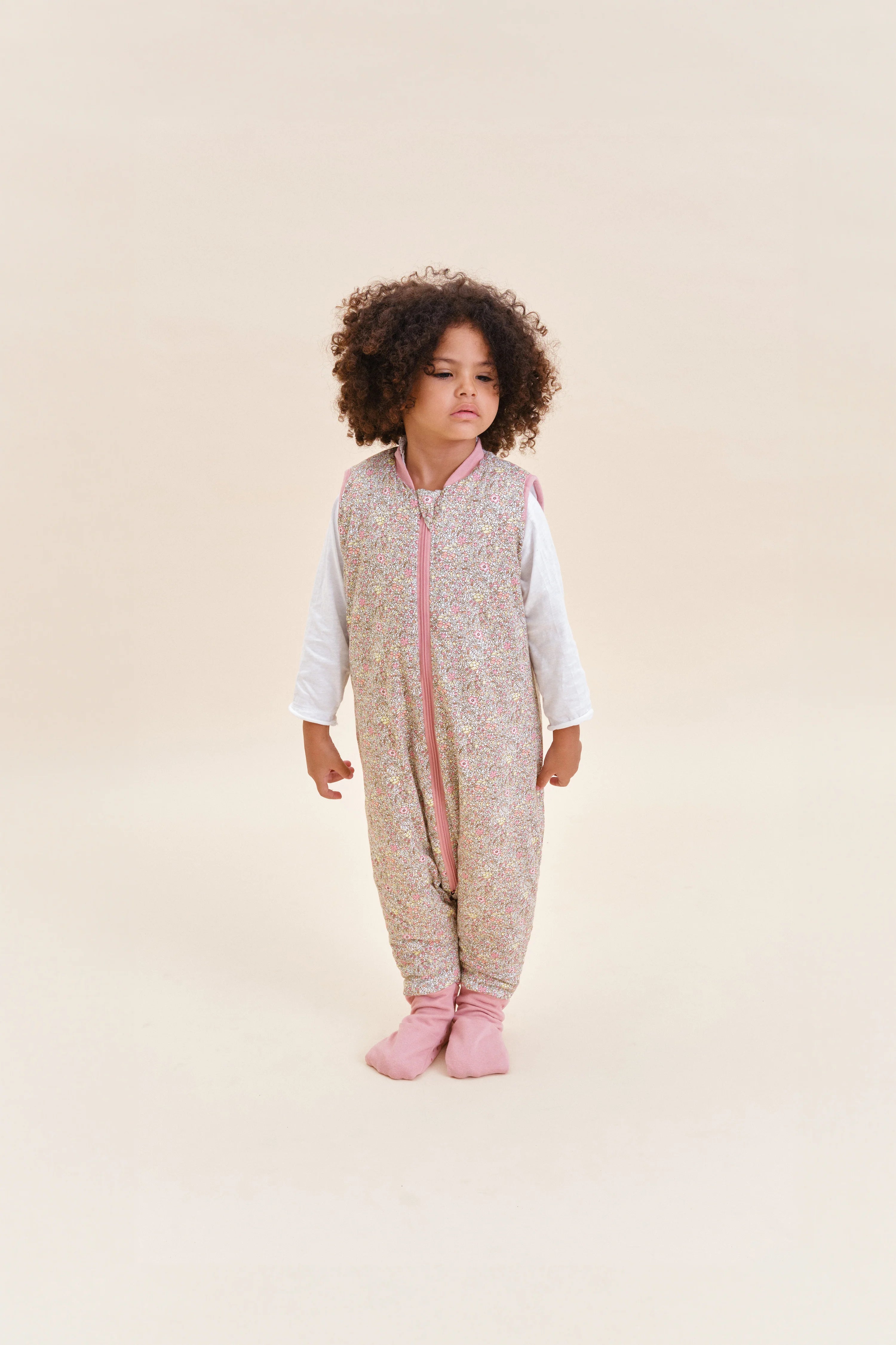 Criança com saco de dormir MolisandCo TOG 2.5 Pastel Floral e meias antiderrapantes, em pé.