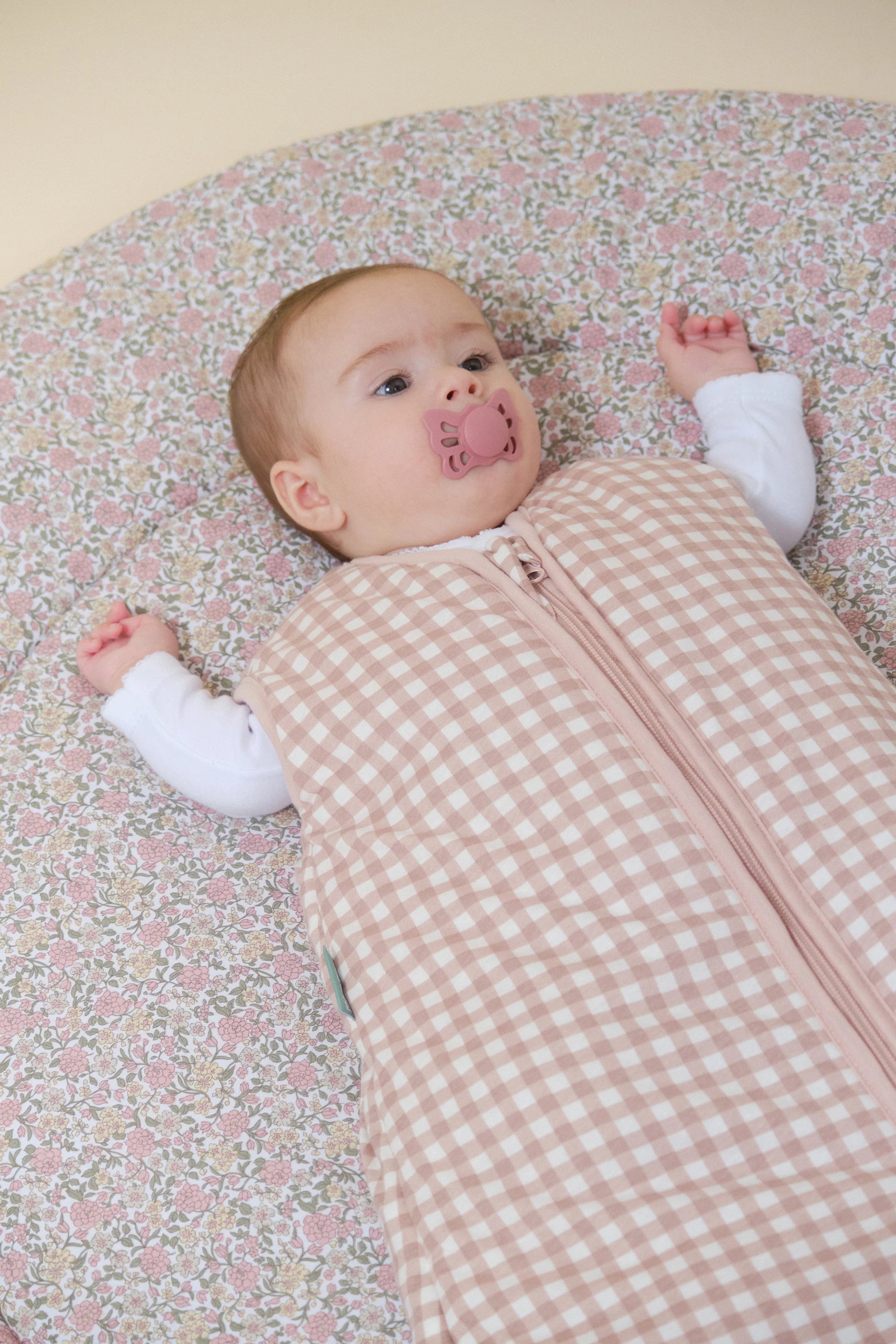 Close-up de bebé com saco de dormir MolisandCo TOG 2.5 Dusty Rose xadrez. Detalhe do tecido e fecho.