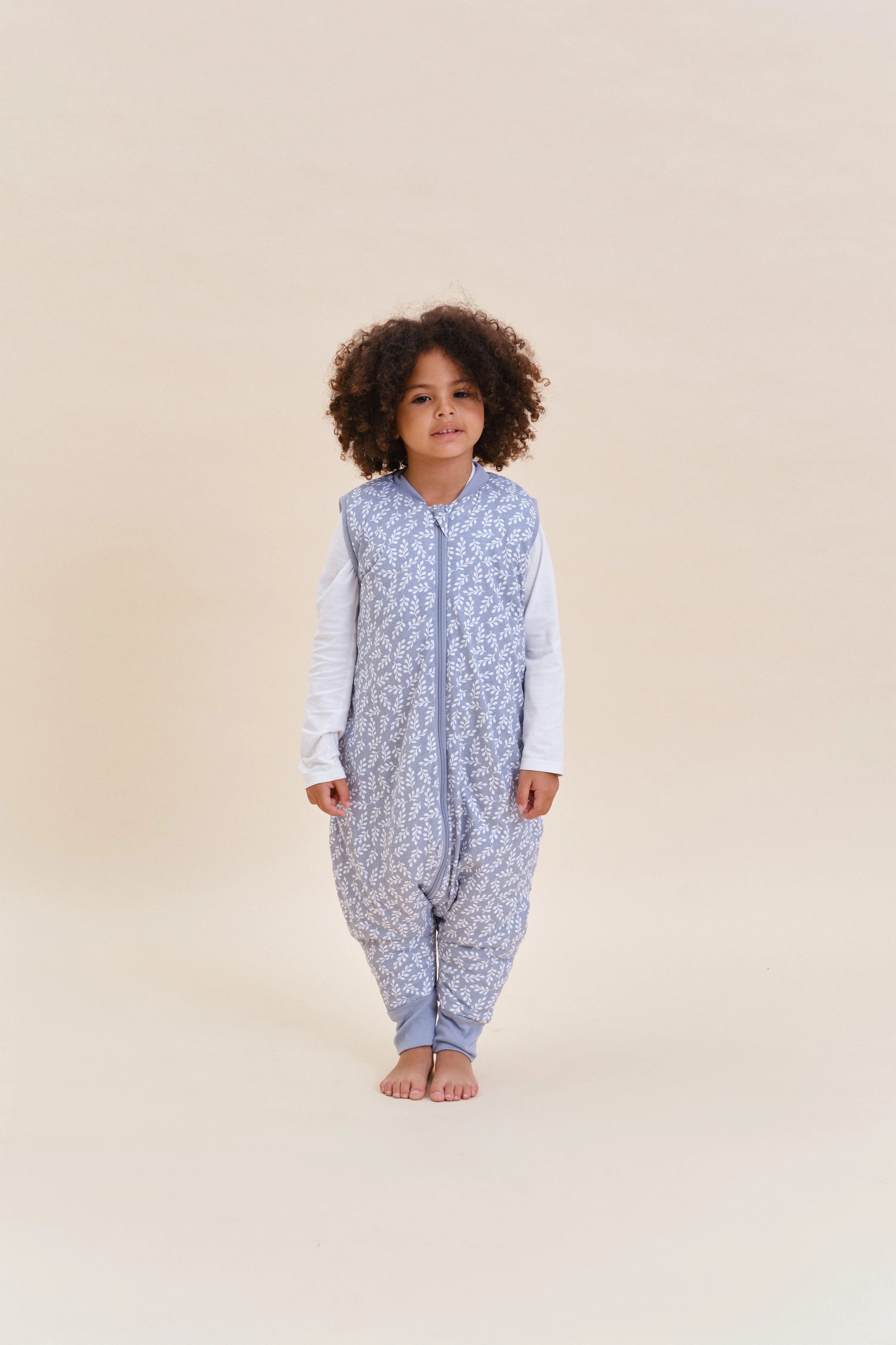Menina com saco de dormir MolisandCo TOG 2.5 Blue Garden, vista frontal, destacando o padrão e design.