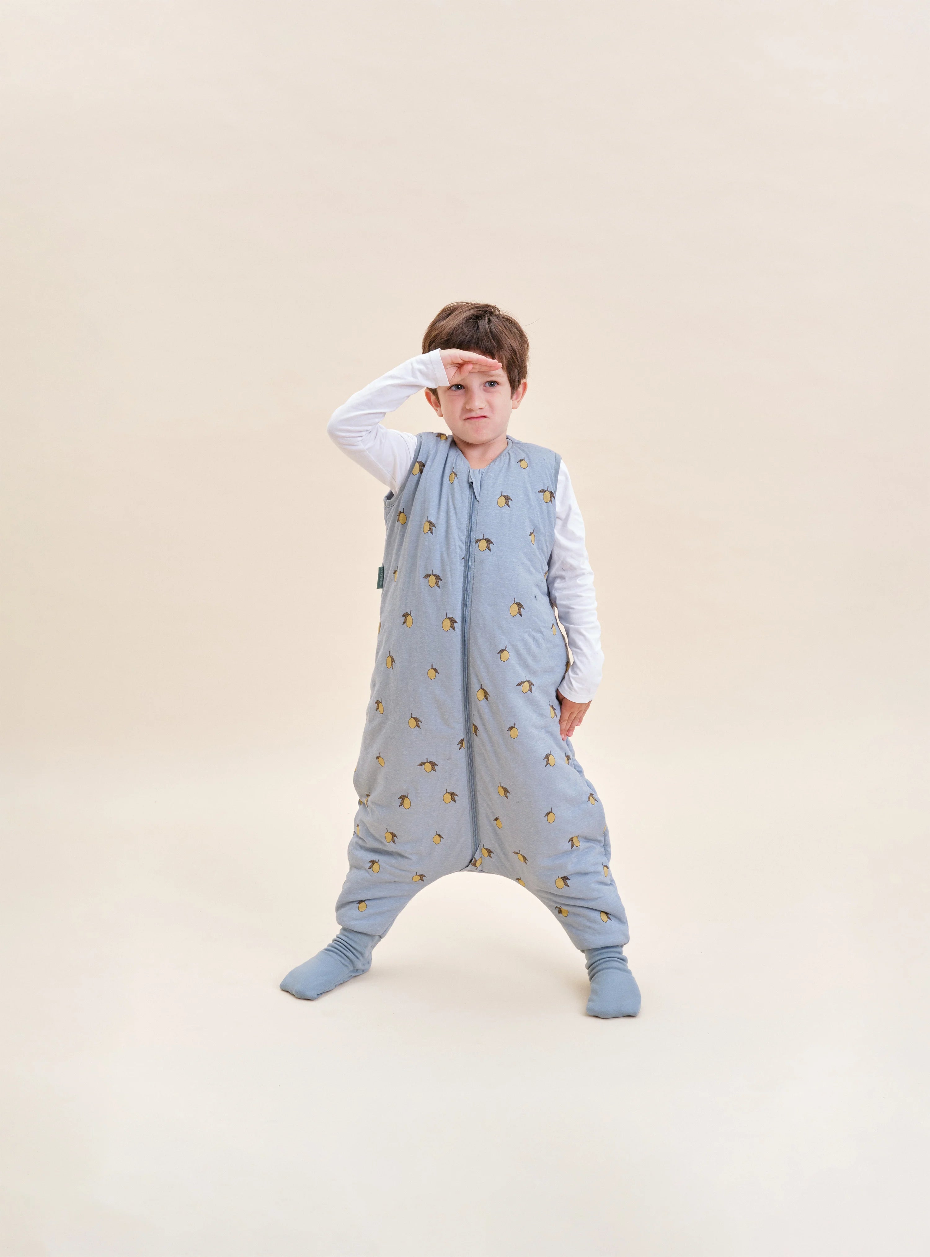 Menino com saco de dormir MolisandCo TOG 2.5 com pés Colima, em pose divertida, mostrando liberdade de movimento.