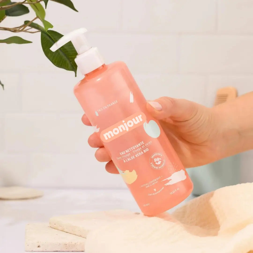 Mão segurando o frasco de Monjour Água Lavante. Ideal para a higiene diária do bebé, sem necessidade de enxaguar.