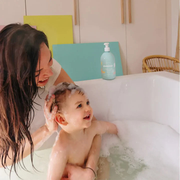 Mãe a lavar o cabelo do bebé com gel lavante Monjour na banheira. Sem alergénios.