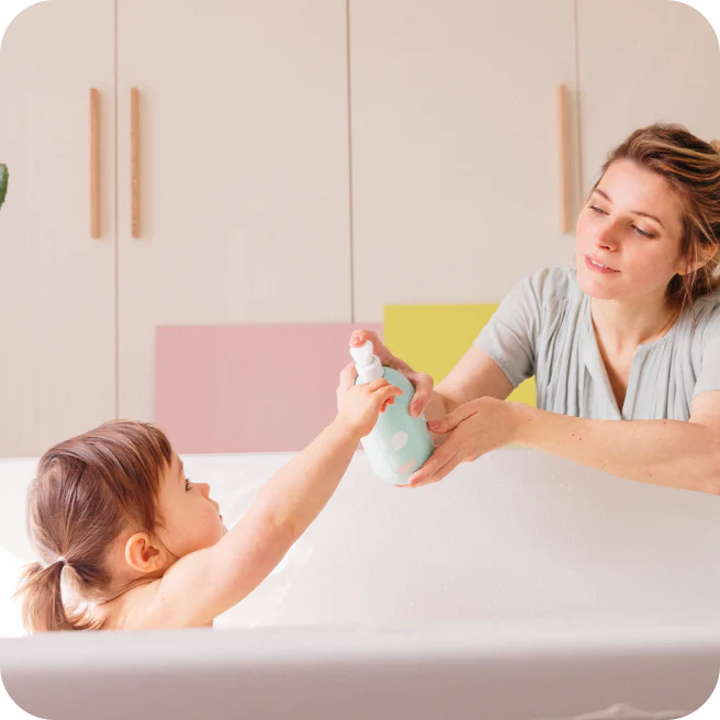Mãe a dar gel lavante Monjour à filha na banheira. Gel suave para pele sensível de bebé.