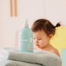Gel lavante Monjour para cabelo e corpo em cima de toalhas macias com bebé ao fundo. Hipoalergénico.