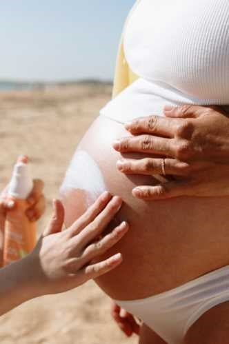 Grávida aplicando protetor solar Monjour SPF 50+. Seguro para grávidas e bebés a partir de 1 ano.