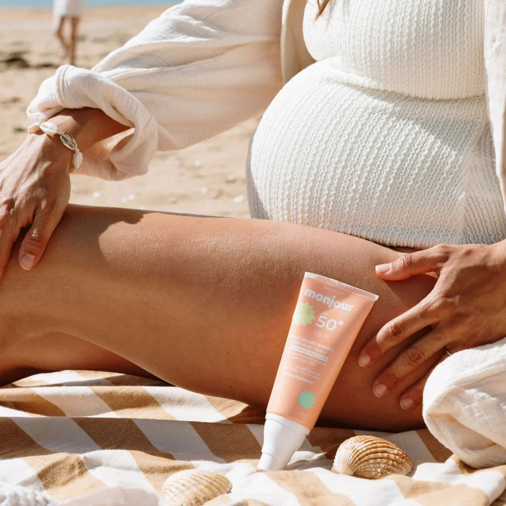Mulher grávida na praia com Monjour Protetor solar SPF 50+ Hipoalergénio spray, seguro para grávidas.