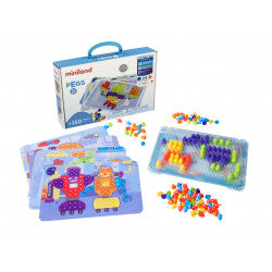 Kit Miniland Pegs 150 peças 15mm completo, mostrando a caixa, o tabuleiro transparente com peças encaixadas, as folhas de design e um monte de peças soltas coloridas.