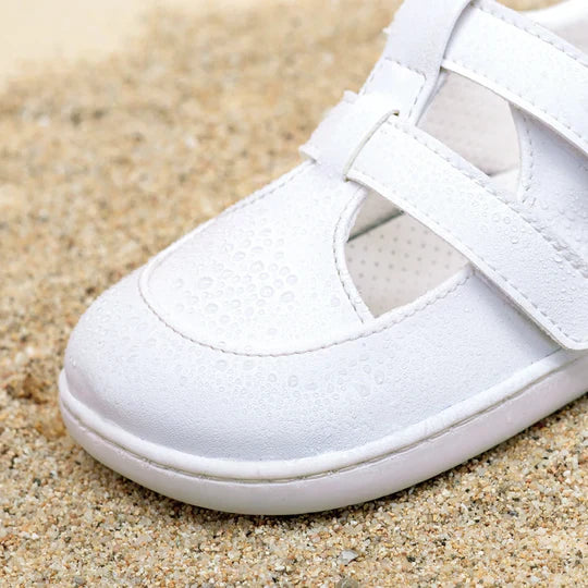 Detalhe do Muris Barefoot Fiji Mini Off White na areia, mostrando a sola flexível e o design respeitador do pé. Modelo confortável e respirável para todas as ocasiões.

