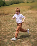 Criança a correr no campo com os Muris Barefoot Nuuk Junior Taupe, evidenciando a leveza e flexibilidade do calçado barefoot.

