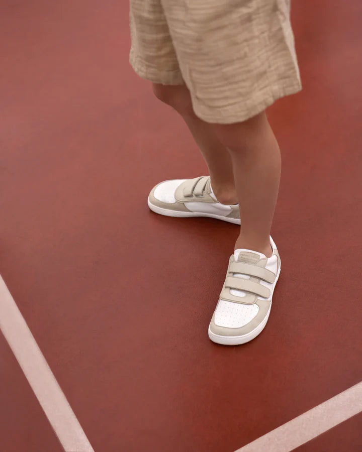 Criança a usar os Muris Barefoot Petra Junior Stone na quadra, evidenciando a leveza e flexibilidade do calçado barefoot.

