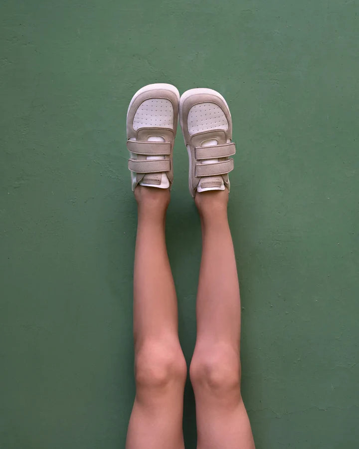 Vista superior dos Muris Barefoot Petra Junior Stone nos pés de uma criança, destacando o design minimalista e os fechos em velcro.

