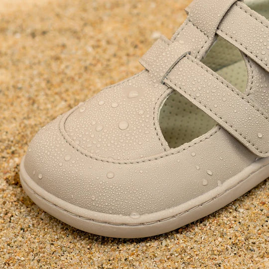 Detalhe em close-up da ponta da sandália Muris Fiji Mini taupe, mostrando gotas de água na superfície, destacando a resistência e o material vegetal.